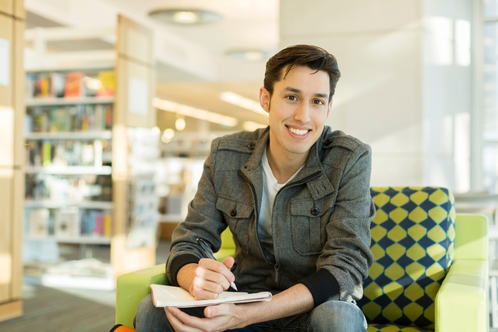 Student writing notes in a spiral notebook